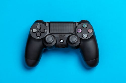 黑色索尼ps4游戏控制器在蓝色背景上的平躺照片 · 免费素材图片