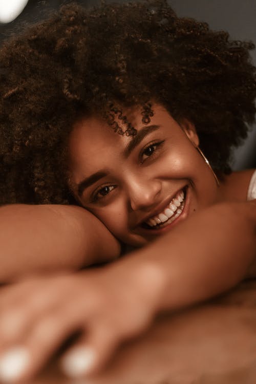 微笑的女人，她的头ans手放在木质表面上的特写照片 · 免费素材图片