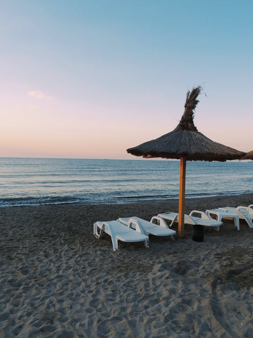 日光躺椅在海边沙滩上的照片 · 免费素材图片