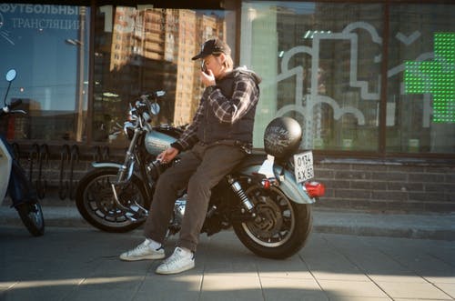 坐在摩托车上的黑色连帽外套的男人 · 免费素材图片