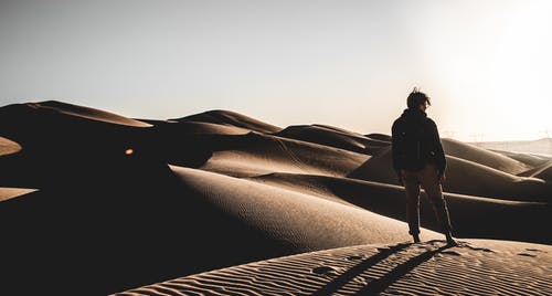 一个人站在沙漠上的背影照片 · 免费素材图片