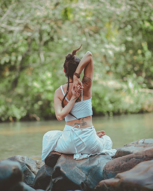 坐在水附近做瑜伽的女人的背影照片 · 免费素材图片