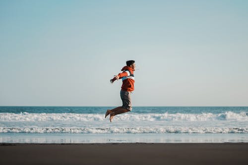 男子在海边跳跃的照片 · 免费素材图片
