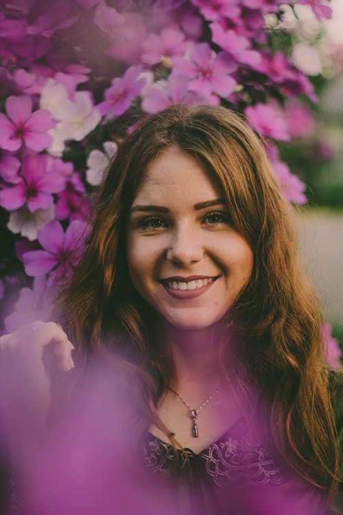 女人在紫色的花朵附近的选择性焦点照片 · 免费素材图片