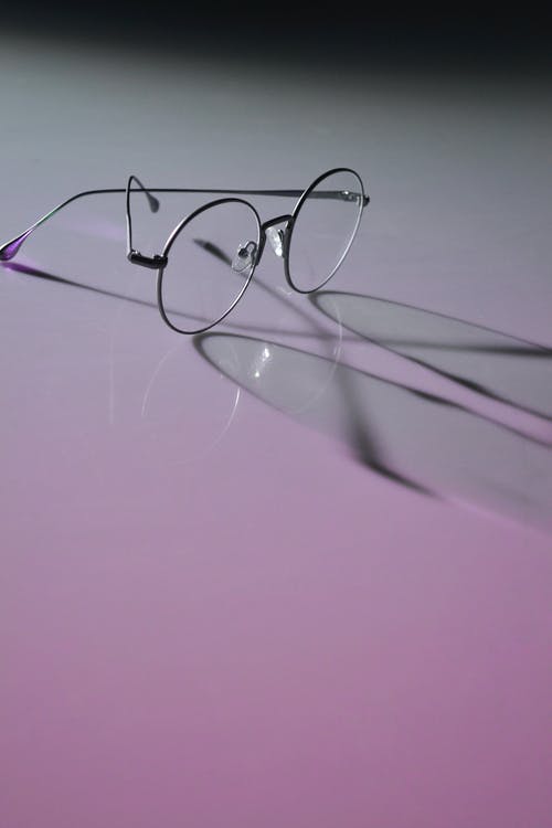 圆形眼镜在白色表面上的照片 · 免费素材图片