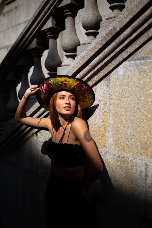 戴着太阳帽倾斜在楼梯上的女人的照片 · 免费素材图片