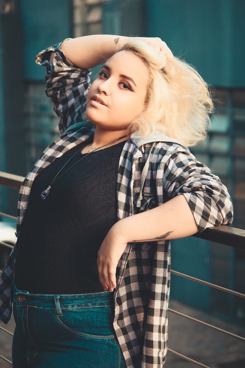 倾斜在栏杆上时握住她的头发的女人的照片 · 免费素材图片