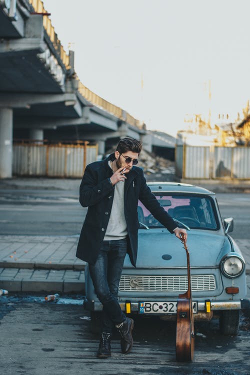 站在旧车前吸烟的人的照片 · 免费素材图片