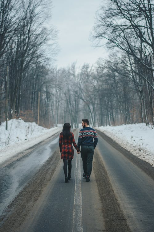 夫妇在光秃秃的树木附近的道路上行走的照片 · 免费素材图片