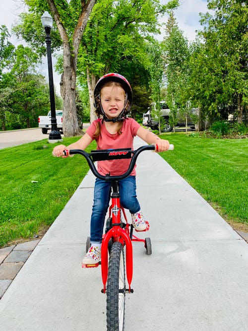 小女孩骑自行车的人行道上的照片 · 免费素材图片