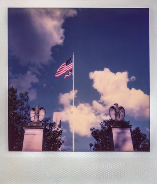 美国国旗飘扬在两鹰雕像之间的杆子上 · 免费素材图片