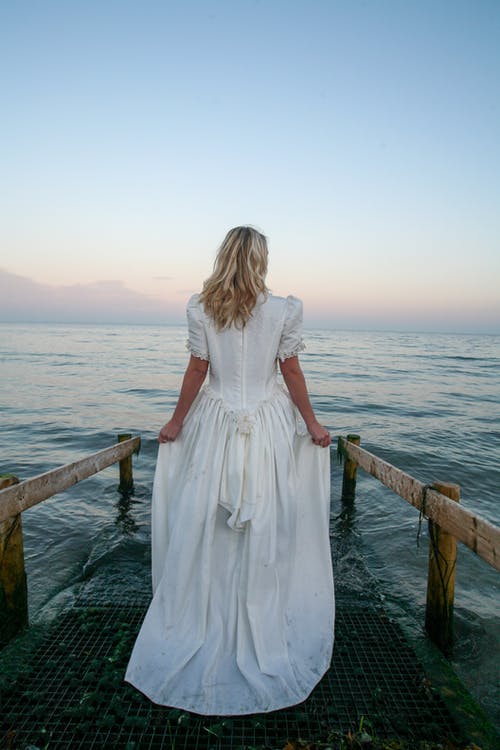 女人站在附近的水体的背影照片 · 免费素材图片