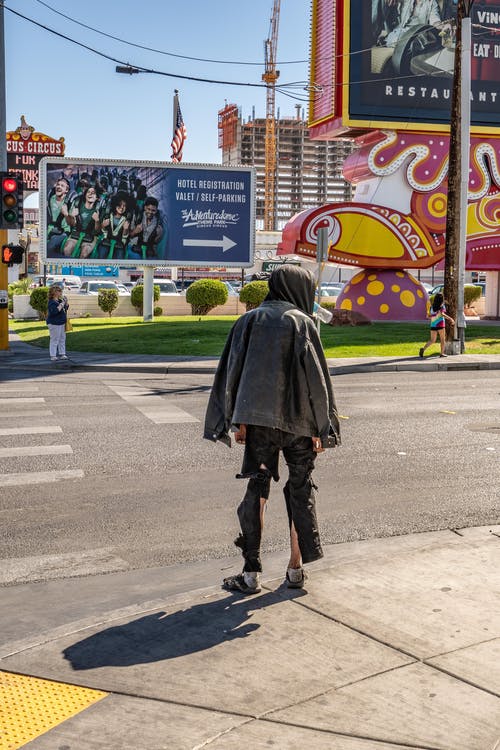 穿着灰色夹克站在人行道上的人的背影照片 · 免费素材图片