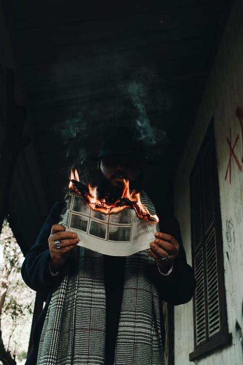 男子手持燃烧纸的低角度照片 · 免费素材图片