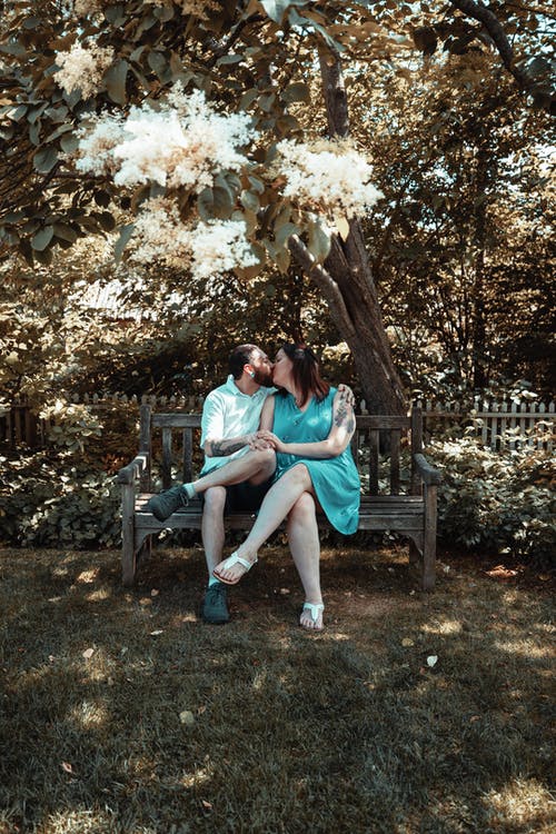 男人和女人坐在长椅上接吻 · 免费素材图片