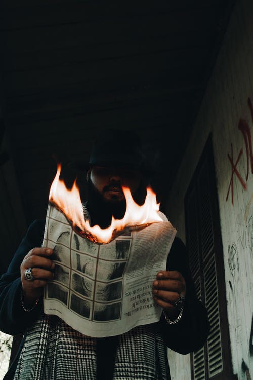男子手持燃烧的报纸的低角度照片 · 免费素材图片