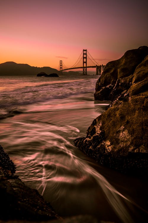 在日落时的橙色天空下的旧金山大桥 · 免费素材图片