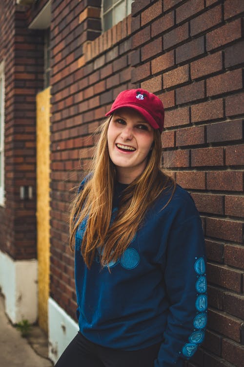 蓝色的长袖衬衫，倚在墙上的女人 · 免费素材图片