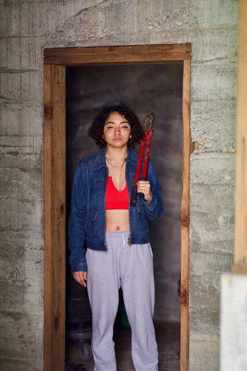 女人抱着红色螺栓切割机站在门口的照片 · 免费素材图片