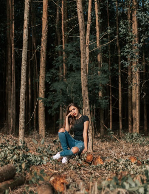 女人在树林里坐在日志上的照片 · 免费素材图片