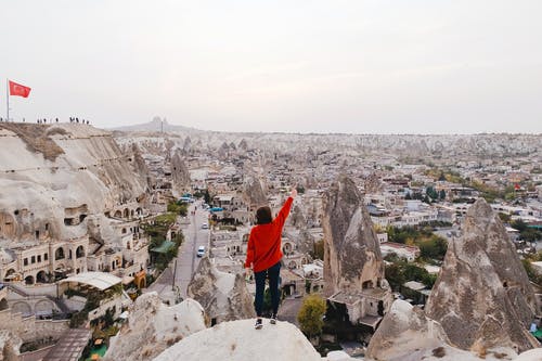 穿红色长袖衬衫站在岩石上的人 · 免费素材图片