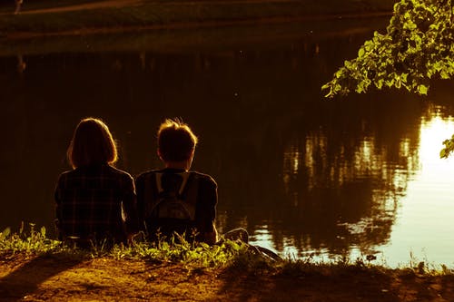 女人和男人坐在湖旁边 · 免费素材图片