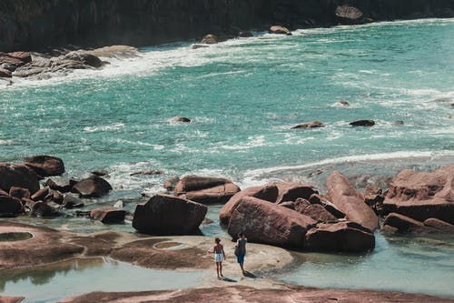 在多岩石的海岸上的人的照片 · 免费素材图片