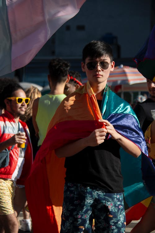 男子手持彩虹色的旗帜 · 免费素材图片