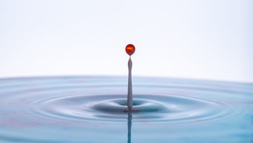 红色和白色的水溅在水面上 · 免费素材图片