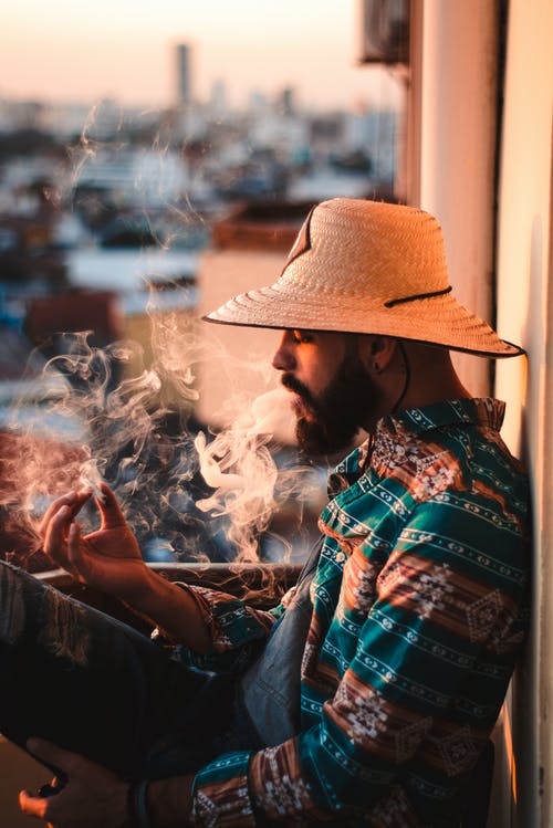 一个男人在棕色和绿色的衬衫吸烟的侧视图照片 · 免费素材图片