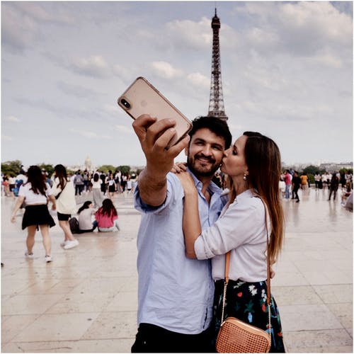 拥抱夫妇与人群和埃菲尔铁塔在后台拍照的合影 · 免费素材图片