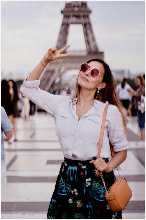 一个穿着白色长袖衬衫站在埃菲尔铁塔附近的女人的照片 · 免费素材图片