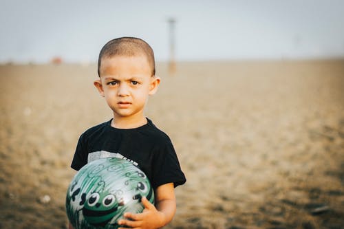 男孩抱着一个球的特写照片 · 免费素材图片