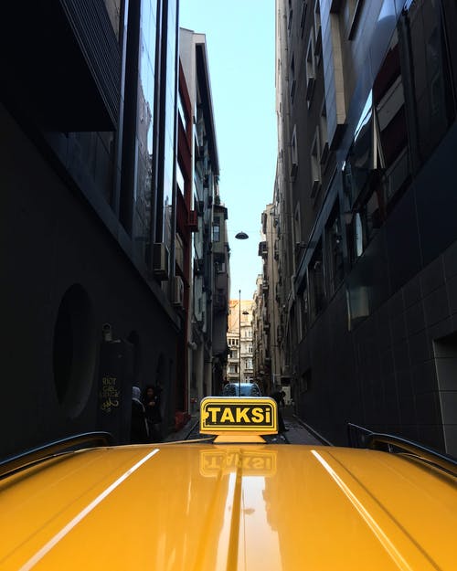 黄色出租车在狭窄的街道上的照片 · 免费素材图片