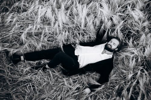 男子躺在草地上的灰度照片 · 免费素材图片