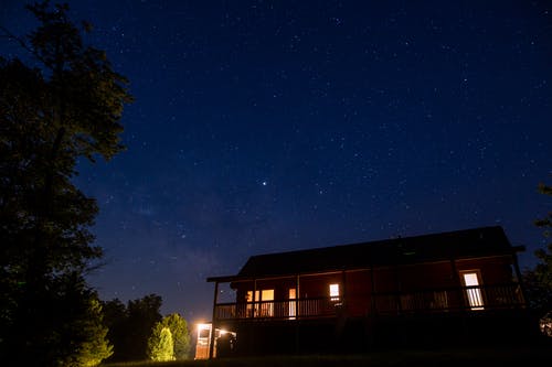 繁星点点的夜空下的点燃的房子的照片 · 免费素材图片