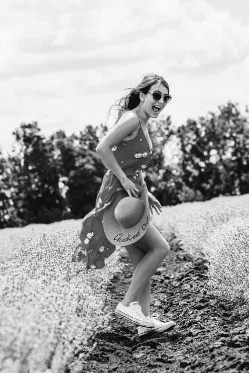 笑女人花裙子站在花场构成的侧视图灰度照片 · 免费素材图片