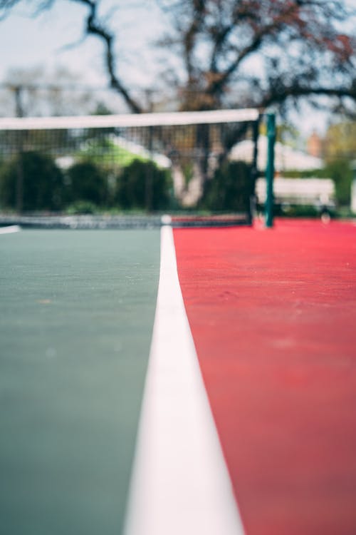 空的红色和绿色网球场的选择性焦点特写照片，带网球网 · 免费素材图片