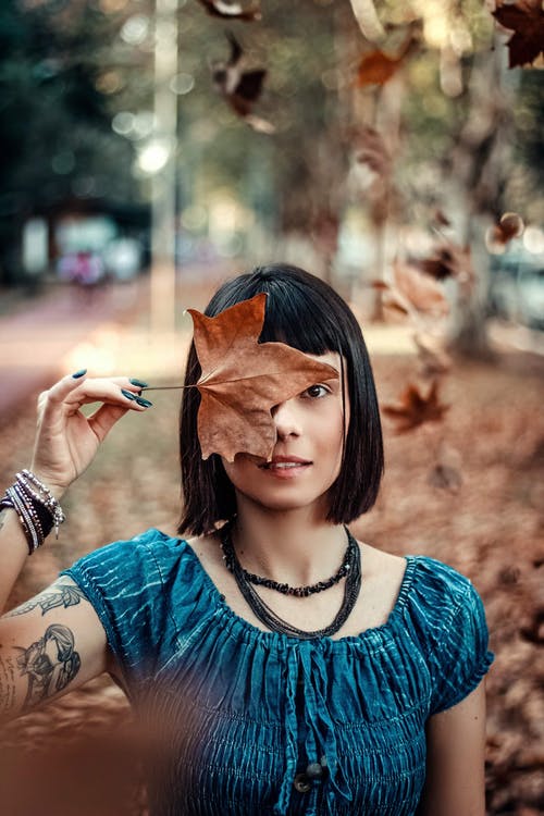 女人拿着干枫叶的照片 · 免费素材图片