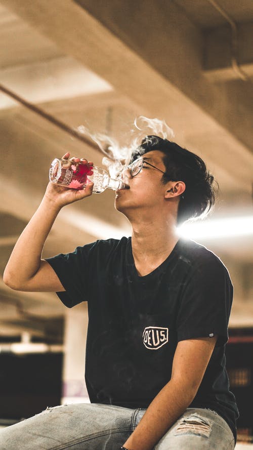 男人穿着黑色圆领衬衫在玻璃瓶上喝 · 免费素材图片