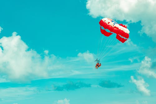 两人骑着红色和白色降落伞的照片 · 免费素材图片