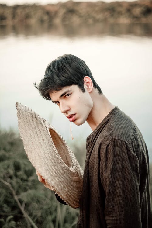 男人穿着长袖衬衫拿着棕色的太阳帽 · 免费素材图片