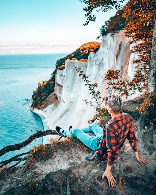 坐在悬崖附近水体的人 · 免费素材图片