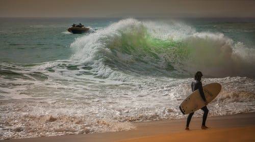 男子在海边携带冲浪板 · 免费素材图片