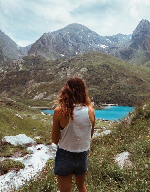 女人在白色背心和蓝色牛仔短裤俯瞰山的背影照片 · 免费素材图片