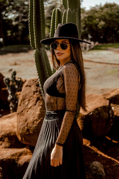 戴着黑色帽子站在仙人掌植物附近的女人 · 免费素材图片