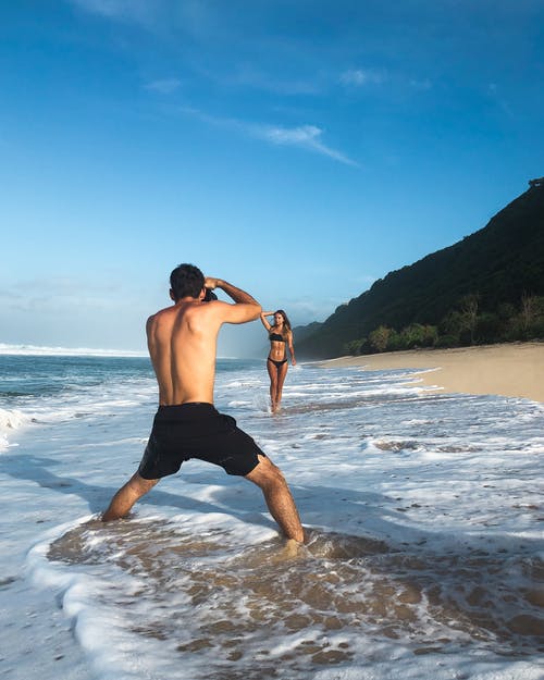 男人拍照的女人站在岸上 · 免费素材图片