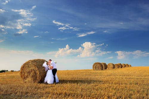 夫妇在干草卷旁边接吻的照片 · 免费素材图片
