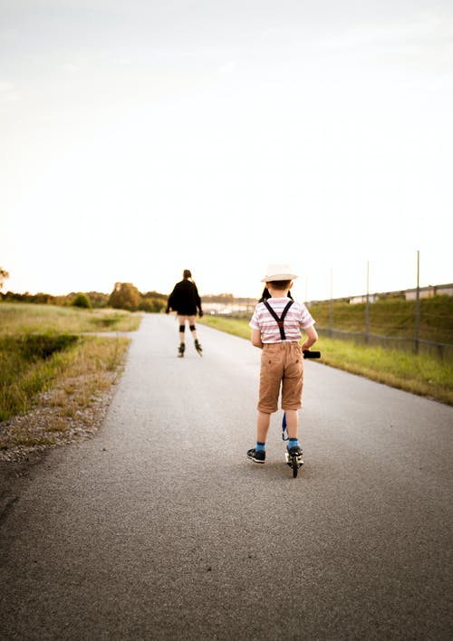 男孩穿着白色和蓝色的短骑踢滑板车 · 免费素材图片