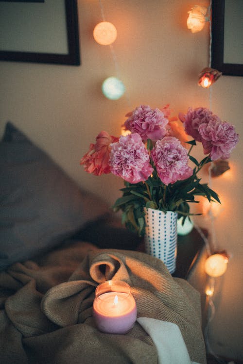 粉色香石竹花附近点燃的茶蜡蜡烛 · 免费素材图片